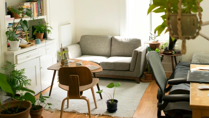 Cozy living room filled with lush indoor plants, natural wood furnishings, and soft neutral tones, highlighting how woven wood shades complement organic interior design.