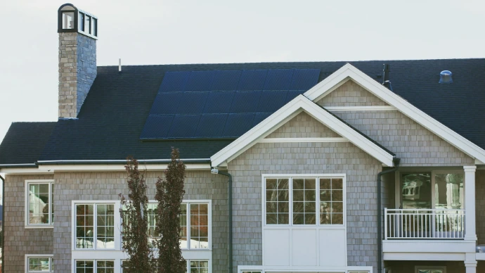 Energy-effcient home with rooftop solar panels and large windows, highlighting how insulating cellular shades can improve indoor comfort and energy efficiency.