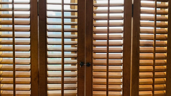 Natural wood plantation shutters with adjustable louvers on multiple windows, offering privacy, filtered sunlight, an timeless architectural style.